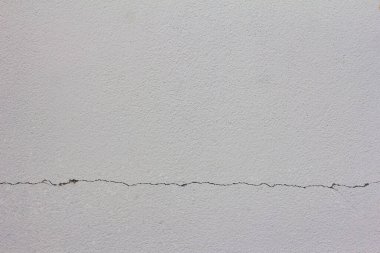 Altında çatlak olan beyaz beton duvar, arka planda boşluk, arka plan ve tasarım için çimento dokusu.