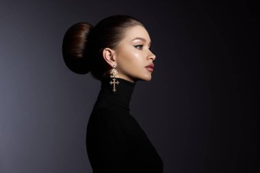 Siyah balıkçı yaka giyen zarif bir kadının moda sanat stüdyosu portresi. Yüksek saçlı, mükemmel profilli bir yüz. Zarif güzellik stili. Kulağında küpeler