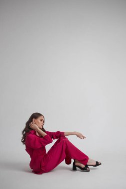 Kırmızı ışıklı takım elbiseli zarif genç bayan yerde oturuyor. Kendine güvenen başarılı kadın.