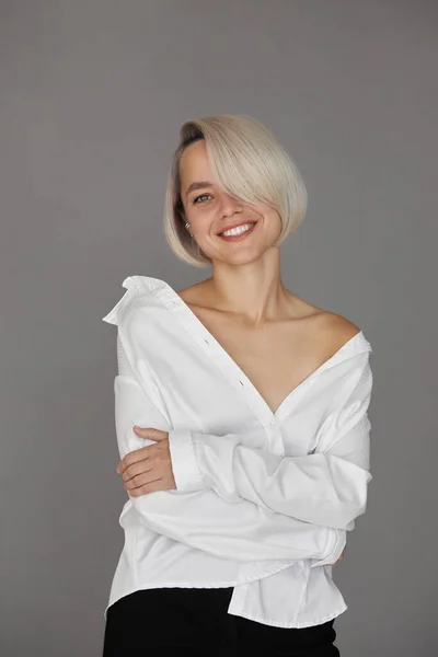 Blonde woman with short dyed hair, short haircut. Hair root care, woman in shirt fashion portrait
