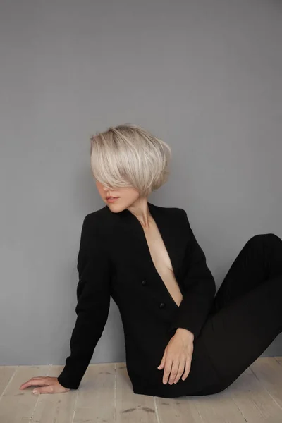Blonde woman, short dyed colored hair, short haircut. Hair root care, woman in black jacket fashion portrait