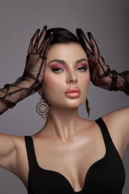Pembe makyajlı, temiz tenli, siyah eldivenli, elinde peçesi olan lüks bir kadının güzel portresi.