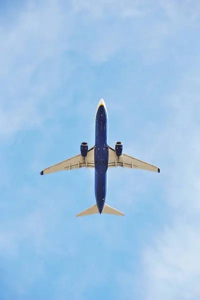 stock image Commercial airplane captured from below as it climbs into the vast blue sky, showcasing its underbelly and jet engines