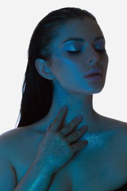 Işıl ışıl cilt makyajlı, yumuşak mavi bir renkle yıkanmış, gözleri kapalı zarif poz veren sakin bir kadın.