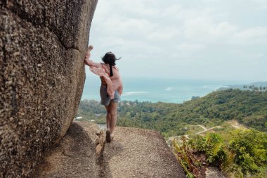 Tropikal bir adada okyanusa bakan bir kadın manzaranın tadını çıkarıyor..