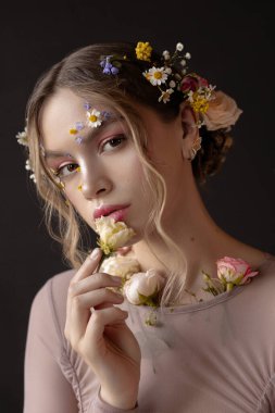 Saçında çiçekler olan bir kadın çöreğin tadını çıkarıyor..