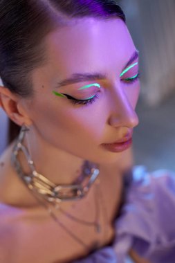 Yaratıcı bir kapalı mekan ortamında, bir manken göz kapaklarında parlak ışıklar bulunan çarpıcı bir makyaj sergiler. Modeller zarif saç stili ve mücevherler büyüleyici görünümü geliştirir..