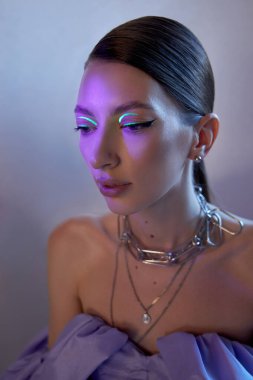 Manken, katmanlı kolyeler ve şık bir kıyafet giyerken kalın çizgilerle çarpıcı neon göz makyajı sergiliyor. şehir arkaplanı sanatsal görünüme modern bir dokunuş ekler.