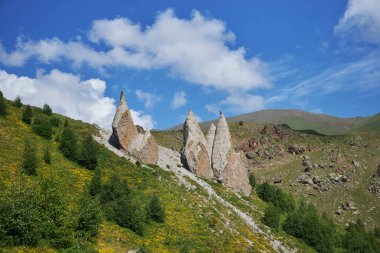 Yükselen taş kuleler yemyeşil bir yamaçta, kabarık beyaz bulutlarla dolu parlak mavi bir gökyüzüne karşı serpilmiştir. Bu ücra bölge doğanın güzelliğini ve tarihini sergiliyor. Kafkaslar