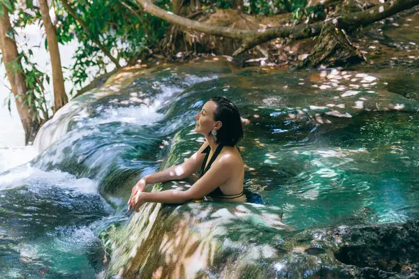 İnsan doğal bir kaynaktaki berrak suda gevşer, canlı yapraklarla çevrilidir. Güneş ışığı yaprakların arasından süzülüp huzurlu bir kaçış için sakin bir atmosfer yaratır..