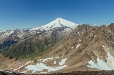 Avrupa 'nın en yüksek zirvesi olan Elbrus Dağı' nın muhteşem manzarası, açık bir yaz gününde engebeli dağlar ve yemyeşil vadilerle çevrilidir..