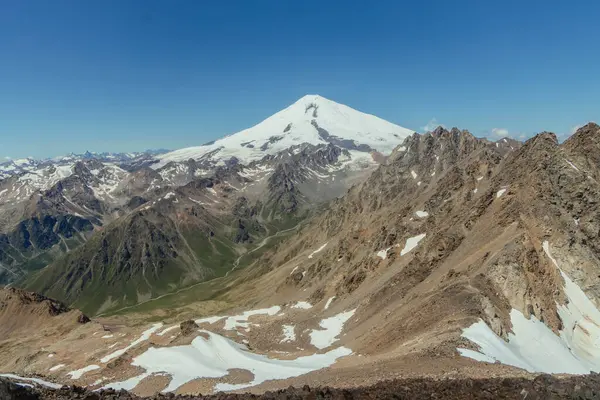 Avrupa 'nın en yüksek zirvesi olan Elbrus Dağı' nın muhteşem manzarası, açık bir yaz gününde engebeli dağlar ve yemyeşil vadilerle çevrilidir..