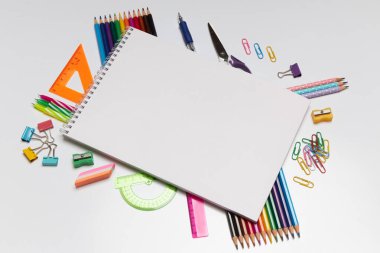 Renkli sabit malzemeler ve çizimler temiz bir yüzey üzerindeki boş bir eskiz defterinin etrafını sarar ve gündüz saatlerinde sanat ve yaratıcılık için davetkar bir atmosfer yaratır..