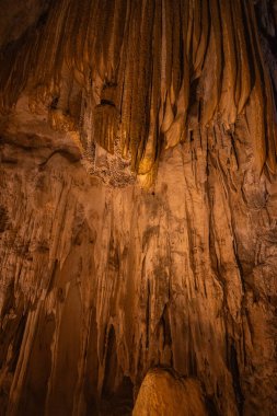Tavandan sarkan buz oluşumları, karmaşık dokularını ve şekillerini vurgulayan yumuşak ışıkla aydınlatılıyor..