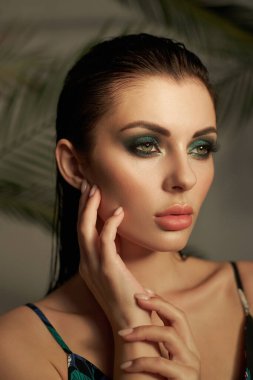 model displays stunning makeup with artistic eyeshadow and flawless skin. She poses gracefully with a thoughtful expression, highlighting her beauty. soft background enhances her features.