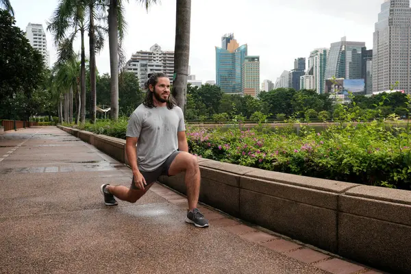 Bangkok, Tayland 'daki Benjakkiti parkında koşudan sonra gerinen bir adam.