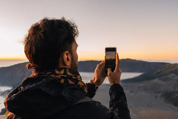 Endonezya 'nın Java şehrinde Bromo Dağı' nın gün doğumunda fotoğrafını çeken turist, sabahları düşük sıcaklık nedeniyle ceket ve eşarp giyiyor.