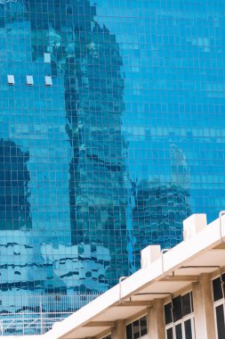 Gökdelenlerin yansımasına sahip modern binanın dikey yakın görüntüsü ve camlarda gökyüzü; Tayland, Bangkok 'taki iş konsepti