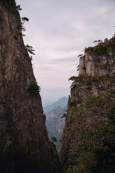 Sonbaharın dramatik manzarasında iki dağ, Huangshan, Çin 'deki Sarı Dağ' da bulutlu bir gün oluşturur.