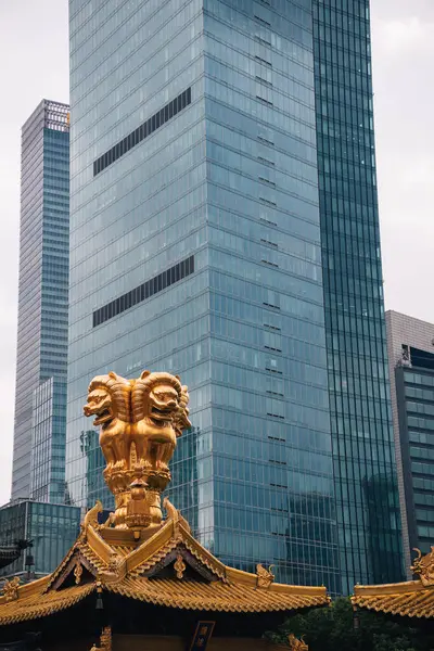Altın aslan heykelleri Jingan Tapınağı 'nın çatısında, Şangay' ın merkezinde bir Budist tapınağı, arka planda bir gökdelen, Çin