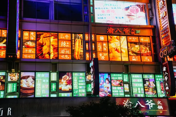 Şangay, Çin; 14 Ekim 2024: Nanjing Yolu 'nda ışıklı neon tabelalar turuncu ve yeşil ışıklarla reklamlanmış yiyecekler sıcak ve soğuk renklerin güzel bir kombinasyonunu oluşturuyor.