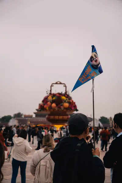 Pekin, Çin; 17 Ekim 2024: Tiananmen Meydanı 'ndaki çiçekli anıtı ziyaret eden bir bayrak ile turist turu