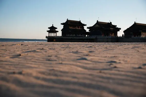 Qinhuangdao sahilindeki Çin tapınağı, Eski Ejder Başı olarak bilinen Çin Seddi 'nin başlangıcına sahip olmakla ünlüdür. Gün batımında kumdan görüntü.