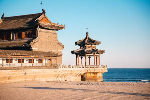 Qinhuangdao sahilindeki Çin tapınağı, Eski Ejder Başı olarak bilinen Çin Seddi 'nin başlangıcına sahip olmakla ünlüdür. Gün batımında kumdan görüntü.