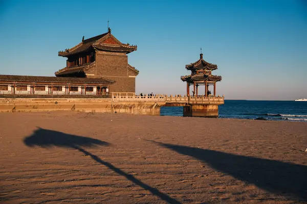 Qinhuangdao sahilindeki Çin tapınağı, Eski Ejder Başı olarak bilinen Çin Seddi 'nin başlangıcına sahip olmakla ünlüdür. Gün batımında kumdan görüntü.