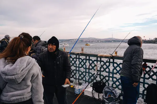 İstanbul, Türkiye; 7 Aralık 2024: Galata Köprüsü 'nden sınır çizen balıkçılar, arka planda Boğaz ve Altın Boynuz bulunan manzaranın keyfini çıkarıyorlar.