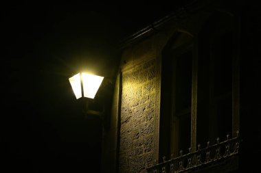 Eski bir İngiliz binasının duvarındaki örümcek ağıyla aydınlatılmış bir sokak lambasının gece görüntüsü. Corbridge ışıkları.