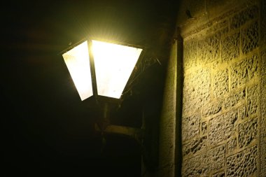 Eski bir İngiliz binasının duvarındaki örümcek ağıyla aydınlatılmış bir sokak lambasının gece görüntüsü. Corbridge ışıkları.