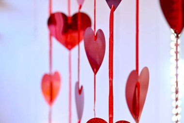 Shiny red heart decorations on the window.  Lots of red hearts joined together with  a thing red ribbon. Love is in the air. Valentine's Day Concept clipart