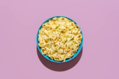 Mor renkli bir masada alfredo yemeği minimalisti olan en iyi manzara. Parmesanlı, tereyağlı, İtalyan tarifli nefis fettucine makarna..