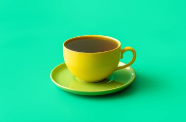 Yeşil renkli bir masada bir fincan çay minimalisti ile yakın çekim. Sağlıklı sıcak içecek, seramik sarı fincanda nane çayı.