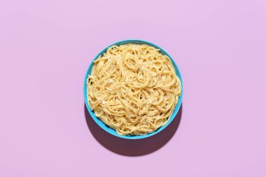 Yukarıdan bakınca, bir porsiyon kakio e pepe, mor bir masada minimalist. Lezzetli İtalyan yemeği, rendelenmiş peynirli spagetti ve karabiber..