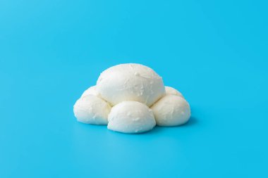Bufalo sütlü mozzarella minimalisti mavi bir masada. Canlı renkli bir arka planda parlak ışık altında taze mozarella topları..