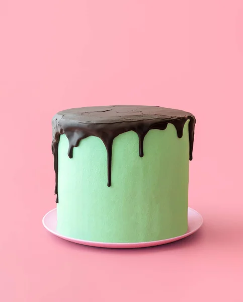 Homemade cake with mint-flavored buttercream and dark chocolate topping. Mint and chocolate cake minimalist on a colorful table.