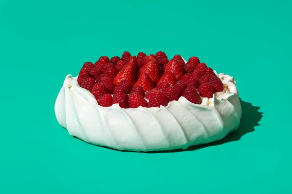 Pavlova cake is a traditional Australian dessert. Delicious summer cake, meringue crust, filled with whipped cream and topped with fresh raspberries and strawberries.