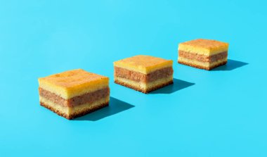 Slices of apple cake aligned on a blue table. Homemade apple layer cake. Square-shaped pieces of apple cake in bright light.