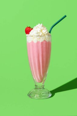 Parlak ışıkta çilek aromalı milkshake yeşil renkli bir masada minimalist. Vanilyalı dondurmalı, çilekli ve kremalı nefis ev yapımı milkshake..