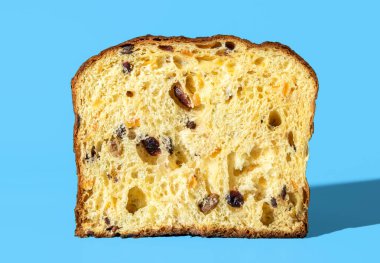Ev yapımı panettone 'dan kesit, mavi masadaki minimalist. Parlak ışıkta ekşi panettone dokusu.