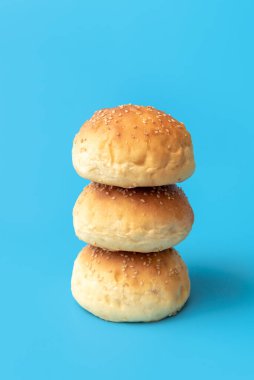 Mavi bir masada ev yapımı hamburger çörekleri minimalist. Taze pişmiş çörekler bir arada..