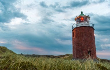 Beautiful sunset scenery on Sylt island, Germany, with an old lighthouse under the cloudy sky. clipart