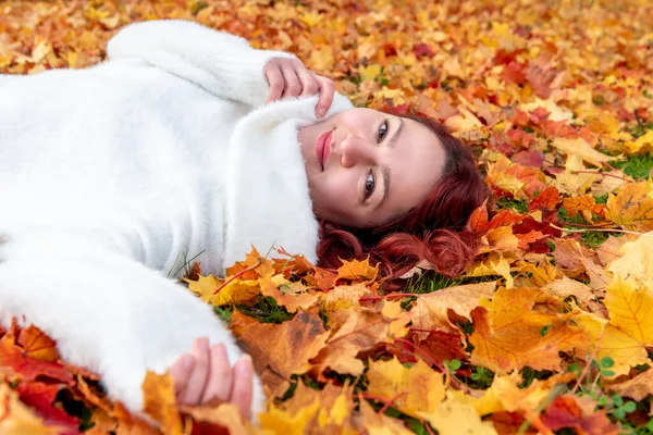 Autumn scenery with a woman lying on the ground surrounded by colorful autumn leaves