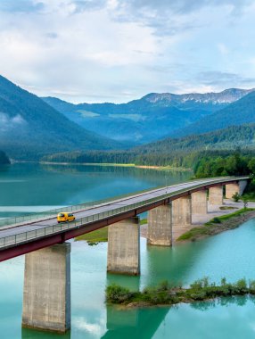 Sylvenstein Gölü ve bir yaz sabahı ufukta Karwendel Dağları üzerindeki köprüyle Alp manzarası