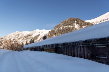 Aralık ayında güneşli bir günde Bavyera Alpleri 'nde dağ kulübesi derin karlarla çevriliydi.