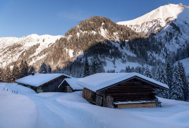 Aralık ayında güneşli bir günde Bavyera Alplerinde dağ kulübeleri derin karlarla kaplıydı.