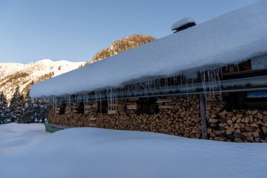 Aralık ayının güneşli bir gününde Bavyera Alplerinde kış manzaralı karla kaplı bir kulübe.