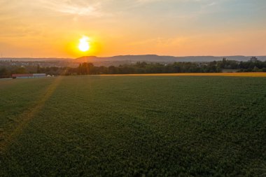 Almanya 'daki Schwabisch Malikanesi' nin hemen dışındaki tarım arazileriyle gün batımında insansız hava aracı görüntüsü.